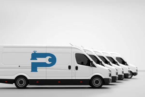 A fleet of white plumbing vans that illustrate the need for commercial vehicle insurance