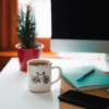 A cozy home office setup with a view of a window, displaying a white mug adorned with a bicycle illustration on a desk, alongside a notepad, pen, and smartphone, symbolizing the planning of home insurance costs in Newfoundland.
